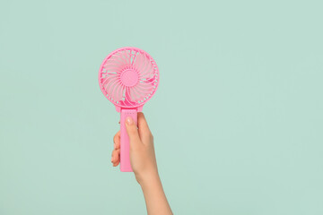 Female hand with mini fan on blue background © Pixel-Shot