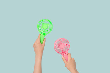 Female hands with mini fans on blue background