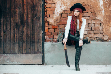 Outdoor portrait of young female in pirate costume with a machete