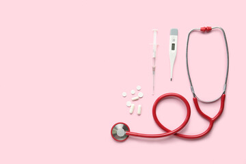 Fototapeta premium Medical stethoscope, pills, syringe and digital thermometer on pink background