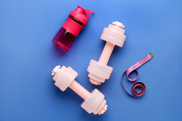 Bottle of water, dumbbells and measuring tape on color background