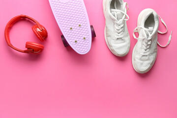 Pair of sneakers, skateboard and headphones on pink background © Pixel-Shot