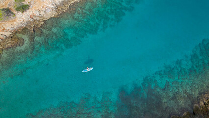 AERIAL TOP DOWN: Female stand up paddler paddling in amazing clear blue sea