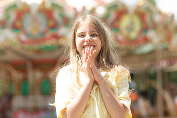Adorable student blonde girl in summer yellow clothes at amusement park. Cute girl stands on the...
