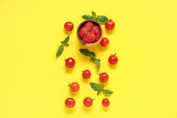 Composition with basil, canned and fresh tomatoes on yellow background