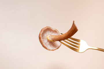 Honey fungi mashroom on a fork on a beige background
