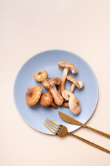 Mushrooms on a plate with cutlery flat lay, top view on beige background