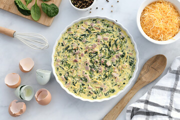 Making a ham, cheese and spinach quiche. Flat lay of ingredients and uncooked quiche.