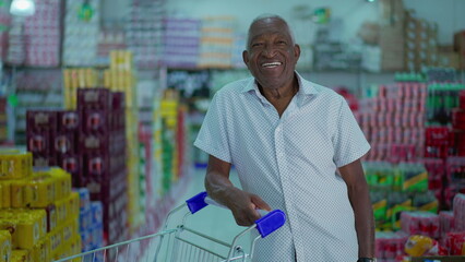 African American shopper smiling at camera standing inside supermarket with shopping cart. One Brazilian black consumer at grocery store