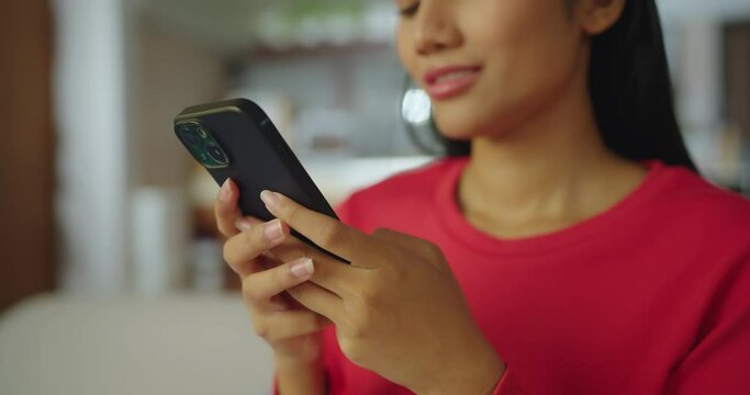 Close-up woman hand using phone in living room at home. She having chat with friend or chatbot in living room.