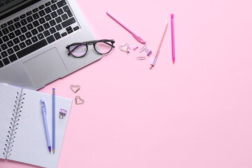 Modern laptop, stationery and eyeglasses on pink background