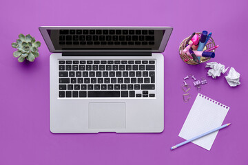 Modern laptop and different stationery on purple background