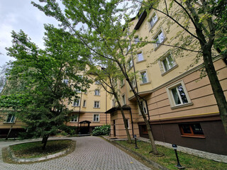 Cozy low house flowerbed with spruce. Quiet courtyard. Entrance to the house. Bright summer photo.