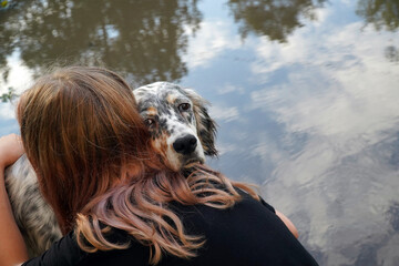 Sad dog . A eleven year-old girl  girl hugs a dog.  Setter.  Farewell to the dog against the water. Concept is best friends