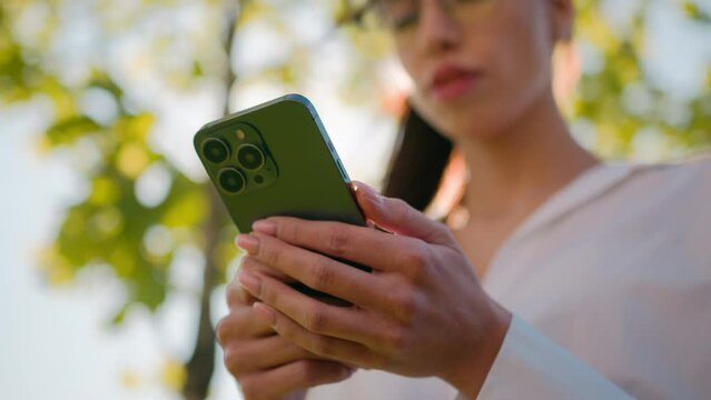 Close-up woman using mobile phone outdoors browsing social network checking email sending electronic sms message on smartphone making order in online shop booking in Internet cellphone new application