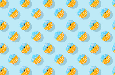 Pattern of blue and yellow  donuts with glaze on blue pastel background