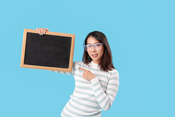 Female Asian teacher pointing at chalkboard on blue background