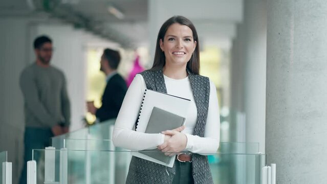 Video of smiling beautiful entrepreneur woman holding some documents while looking at camera in a coworking place