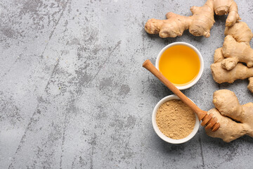 Fresh ginger roots and bowl with dried powder on blue background