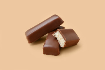 Tasty chocolate covered coconut candies on yellow background