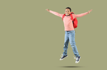 Jumping African-American boy with school backpack on green background