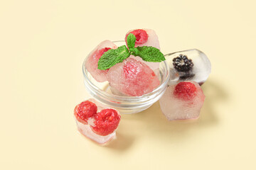 Glass bowl with frozen berries in ice cubes and mint on yellow background