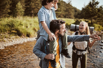 Young family hiking in the forest and crossing a creek together