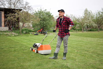 man makes a short break while cutting grass with a lawn mower after at backyard of his house....