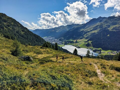 Trail running group runs down above Davos Klosters in the direction of Lake Davos. Running in the mountains. Beautiful trailrun landscape in Switzerland. High quality photo. Trailrun in Davos