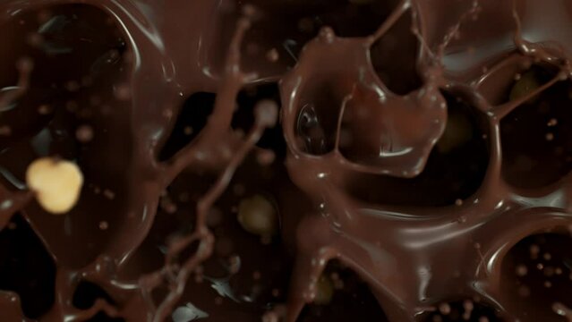 Super Slow Motion Shot of Peeled Hazelnuts Falling into Swirling Melted Chocolate at 1000 fps.