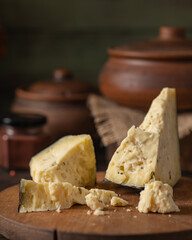 Spicy cheese with ajiga on a wooden board. The table is rustic. Broken into pieces.