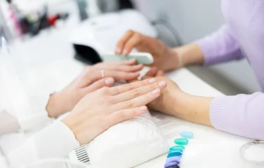  Young woman hands in a nail salon, which the manicure master files the nails with a nail file, giving them shape © JackF