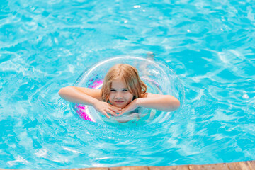 Cute funny teen girl in a swimsuit with an inflatable lifebuoy swims in the pool