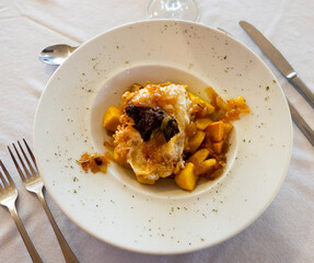Spanish traditional cuisine, Huevos rotos con morcilla on a white ceramic plate