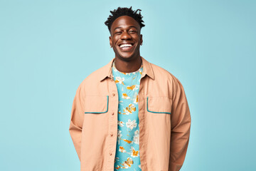 Black man who is smiling and wearing a denim jacket on blue background. The man is looking directly at the camera, and he has a friendly smile on his face.