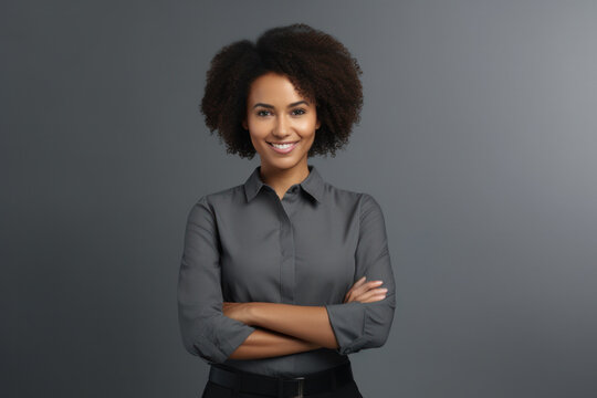 Young African woman posing confidently, hands on waist, looking at camera against grey background. Happy mixed-race woman smiling with copy space.