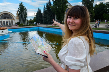 Girl with map points her finger at side at the interesting place of the city. summer holidays, and...
