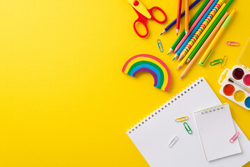 Stimulate interest among parents and educators using a compelling top-down photo showcasing diverse selection of vibrant school supplies. A perfect match for educational campaigns on yellow background