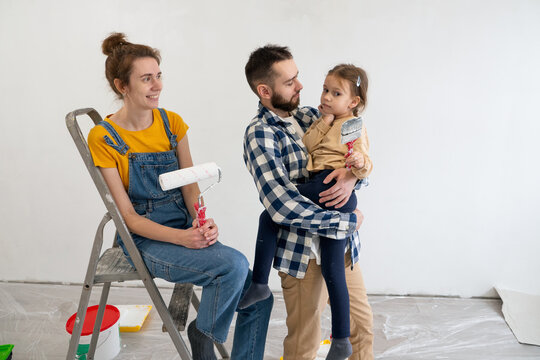 Happy young parents with their daughter having fun with work tools during apartment redecoration and home construction. Renovation and improvement new home