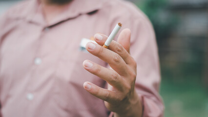 A smoking man is holding cigarette on his hand
