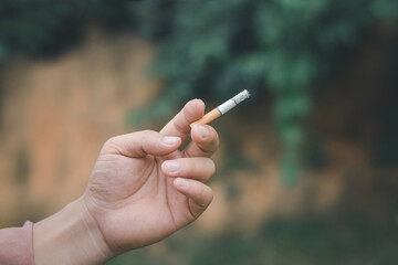 A smoking man is holding cigarette on his hand