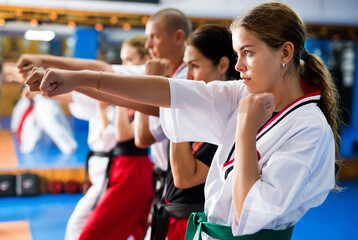 Women and man in kimono training kata movements during group karate classes.
