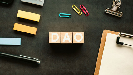 There is wood cube with the word DAO. It is an abbreviation for Decentralized Autonomous...