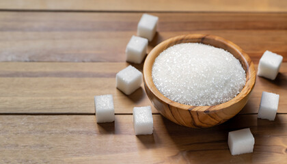 Fototapeta na wymiar White sand sugar in wooden bowl and cube sugar on wood table background.