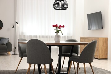 Chairs and table with vase of red rose flowers in dining room. Stylish interior