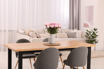 Table, chairs and vase with peonies in stylish dining room