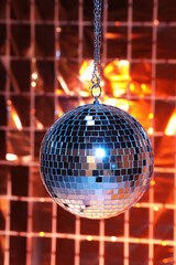 Shiny disco ball against foil party under color lights