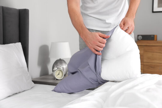 Man changing pillowcase at home, closeup. Domestic chores