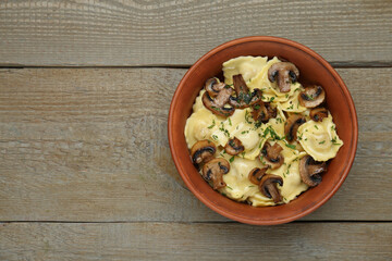 Delicious ravioli with mushrooms on wooden table, top view. Space for text