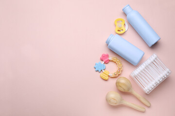 Different skin care products for baby, cotton buds, rattles and pacifier on light coral background, flat lay. Space for text